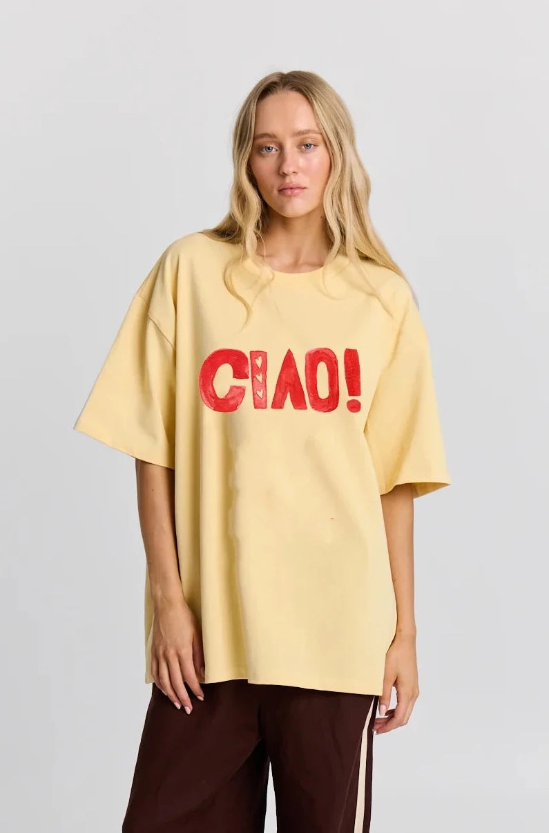 Person wearing a yellow oversized t-shirt with 'CHAO!' text on a plain background