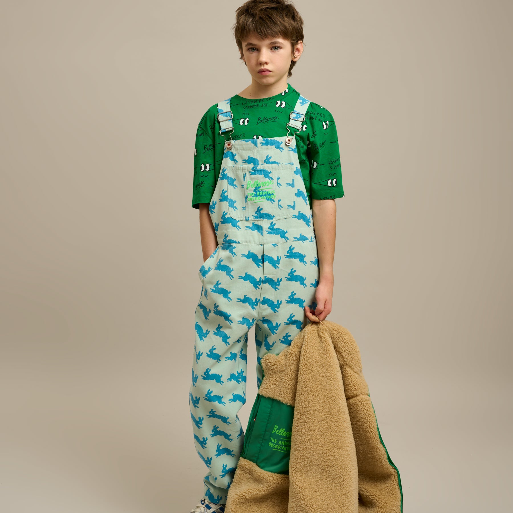 Boy wearing Bellerose X The Animals Observatory t shirt and overalls holding a jacket