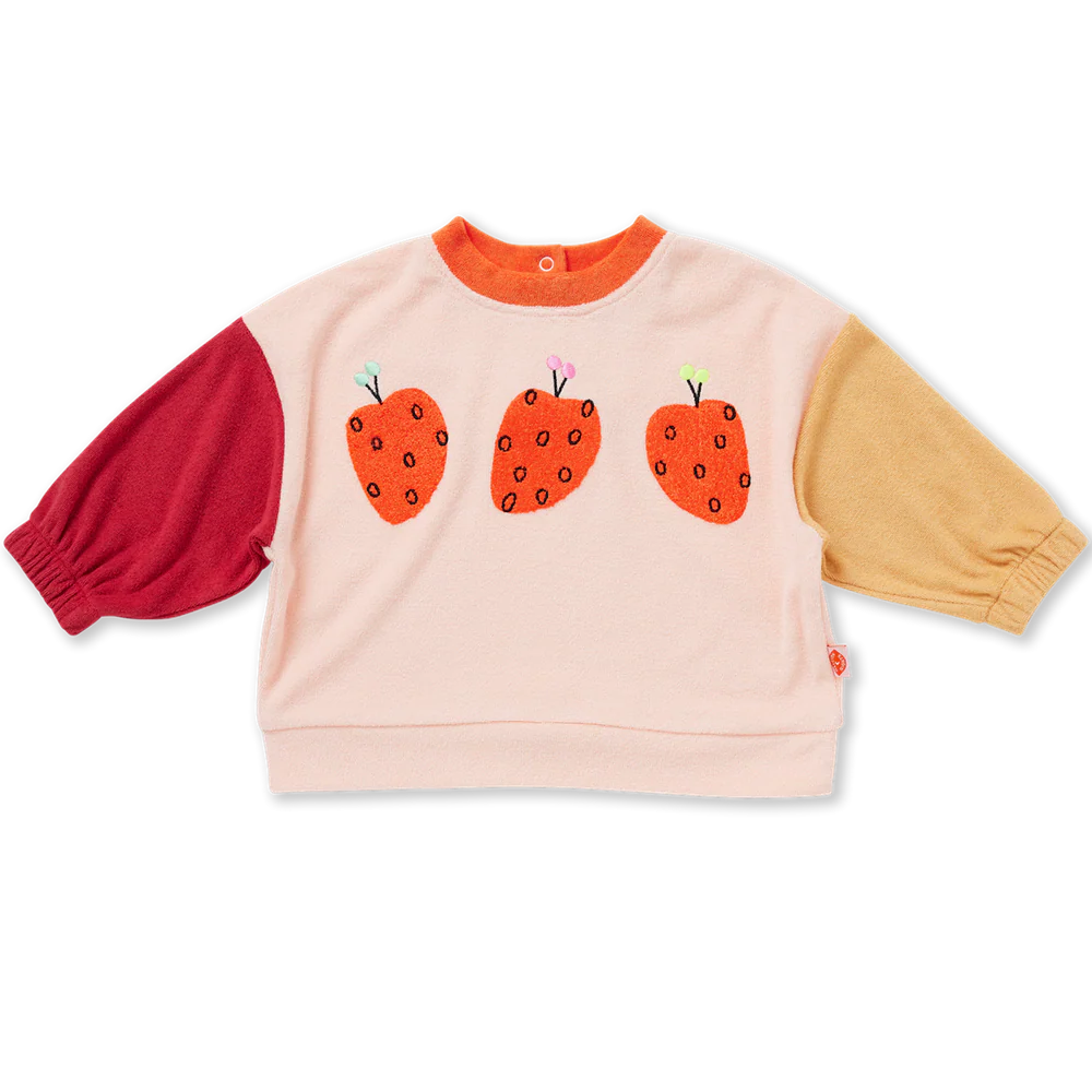 A children's long-sleeve sweatshirt with a light pink body, a red sleeve on the left, and a mustard yellow sleeve on the right. The front features three embroidered orange strawberries with black seeds and small green and purple tops.